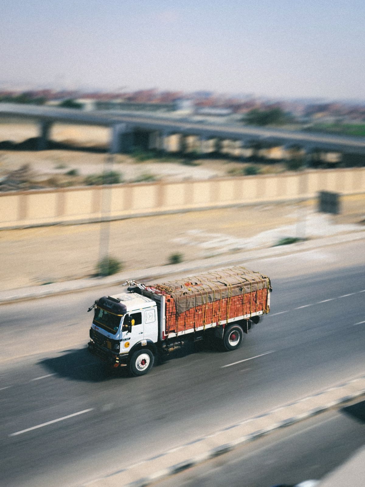 An overhead-loaded cargo truck driving fast down a highway with motion blur, representing image resizing responsibility being delegated to an external CDN instead of Next.js's own server