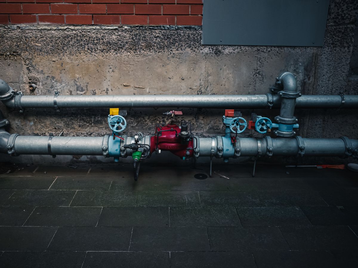 A tangle of colorful industrial pipes and valves on a wall, representing multiple app connections being routed through one shared pooled pipe